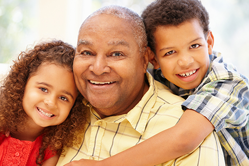 African american Grandfather in yellow shirt smiling with his grandchildren